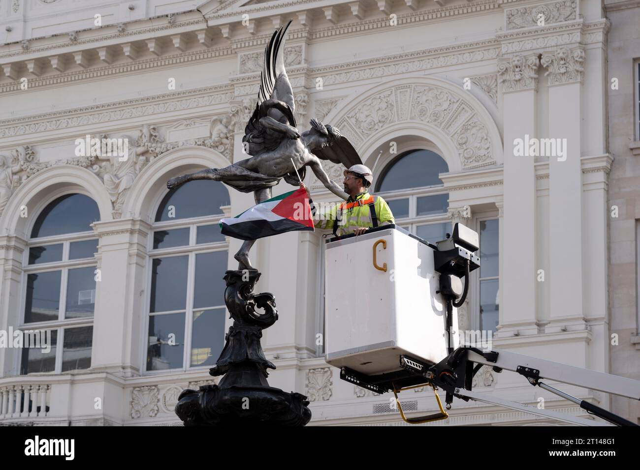Following overnight protests around the capital about the Hamas-Israeli war,  a contractor removes a Palenstinian flag that has been attached to the 'Eros' statue in Piccadilly Circus in the West End of London, on 10th October 2023, in London, England. Stock Photo
