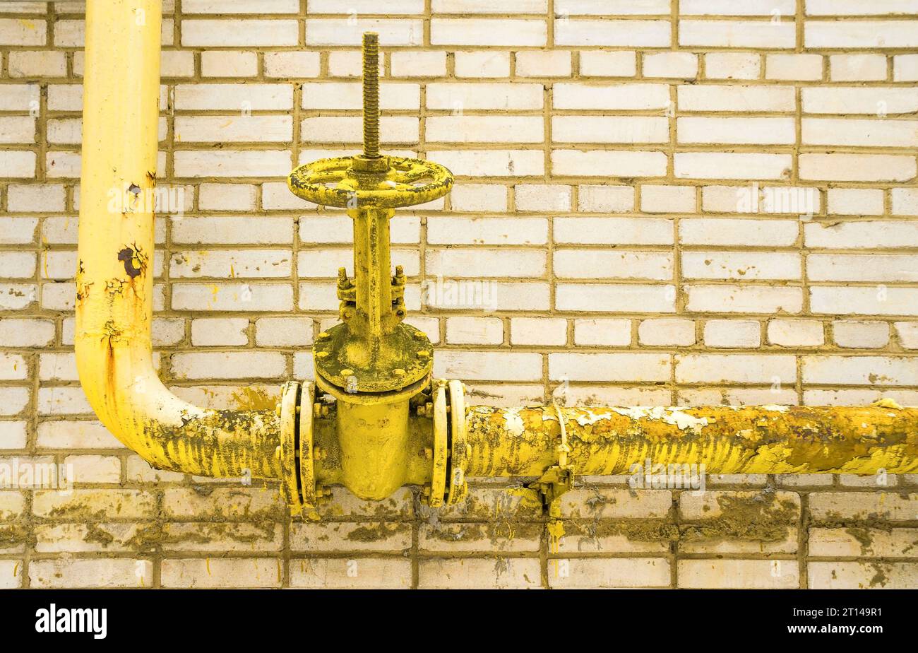 Yellow gas pipe. A latch, the crane on a pipe. Against the background
