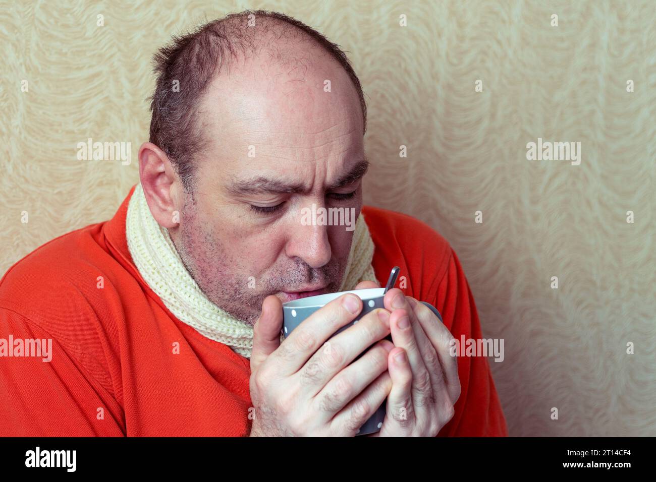 Sick man drinks hotness to recover. The patient holds in his hand a cup