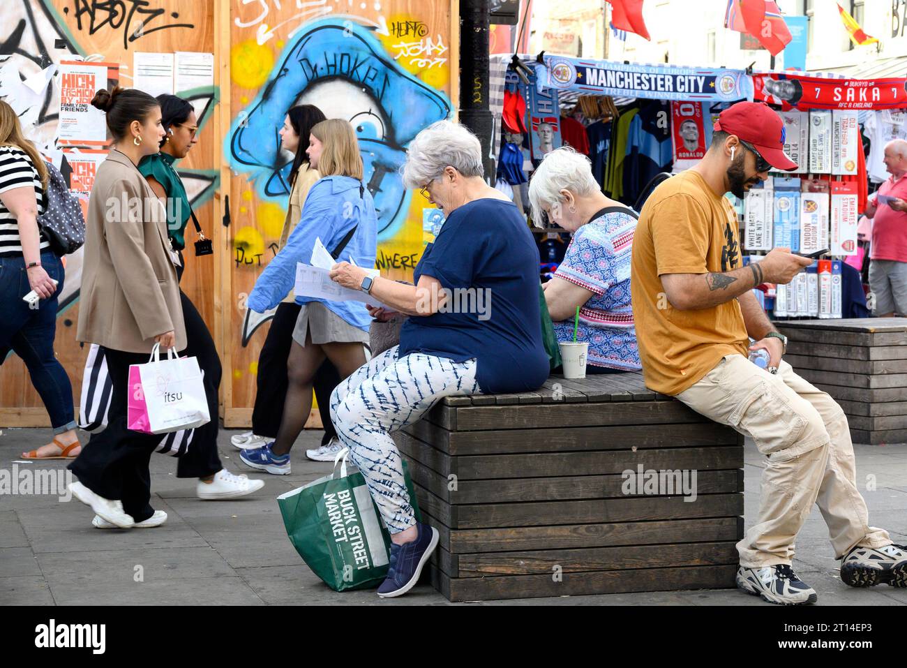 London,UK. Camden Town - people sitting in Camden High Street, looking at a map / mobile phone Stock Photo