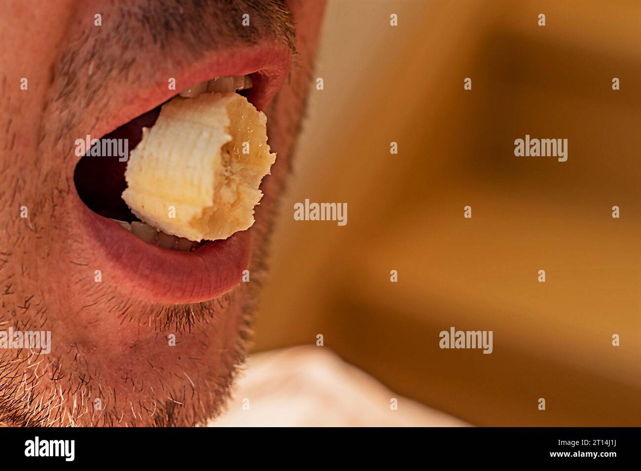 piece of banana in a man's mouth Stock Photo
