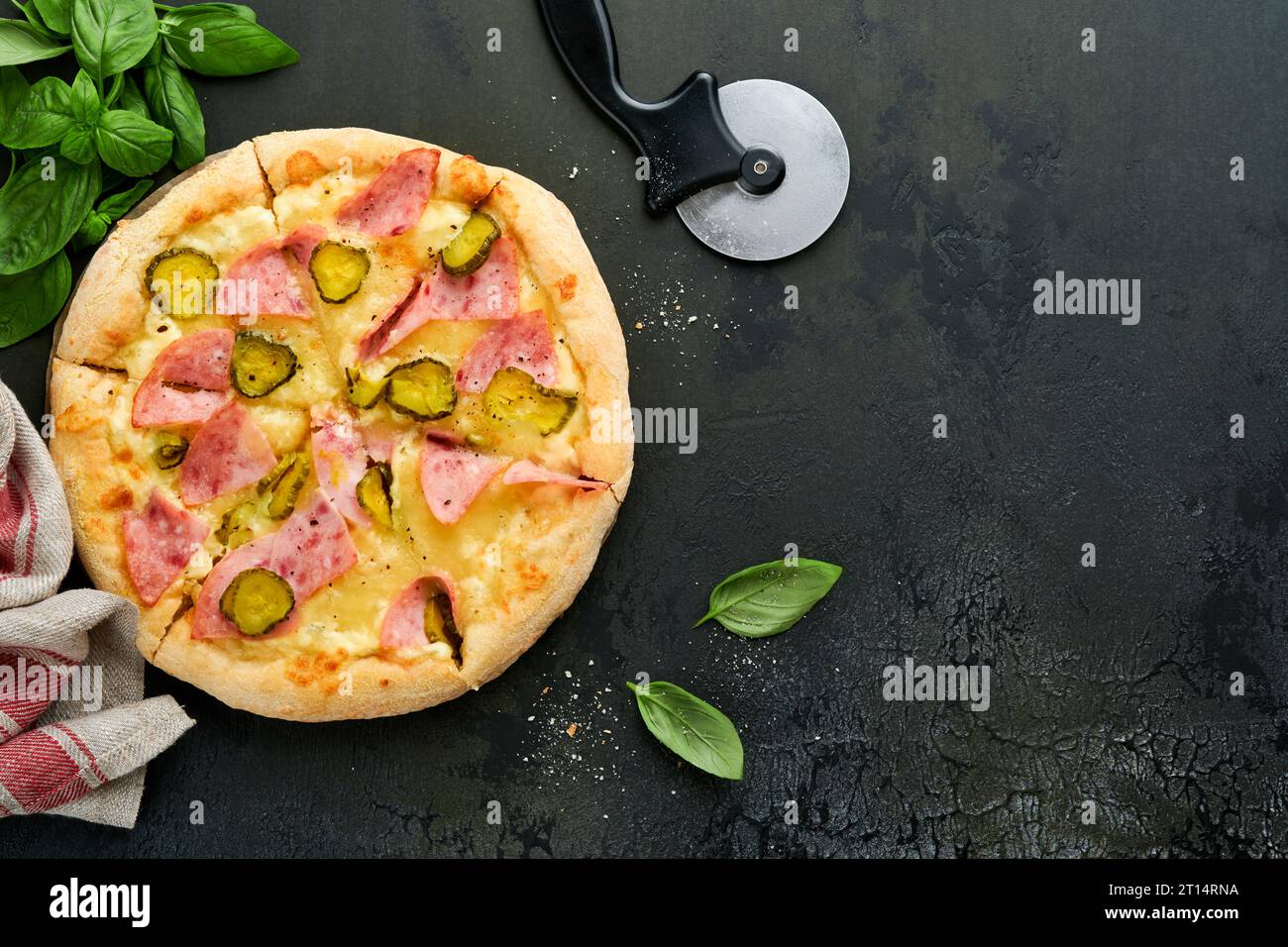 Pizza. Traditional Bacon pizza with ham, mushrooms, pickled cucumber and cheese and cooking ingredients tomatoes basil on wooden table backgrounds. It Stock Photo