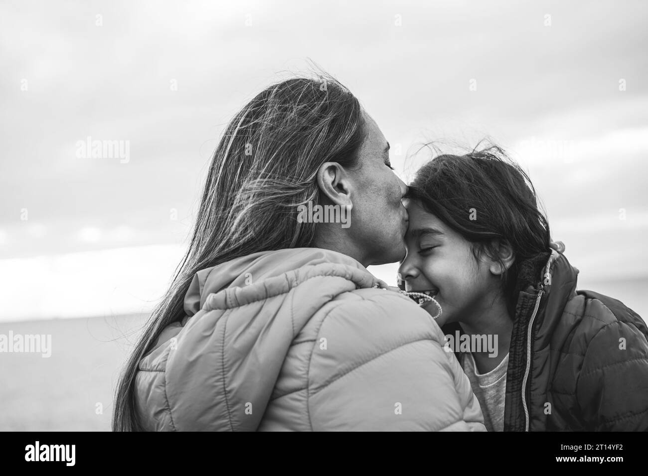 Happy latin mother and daughter having fun during winter time outdoor - Love and family concept - Black and white editing - Focus on mom face Stock Photo