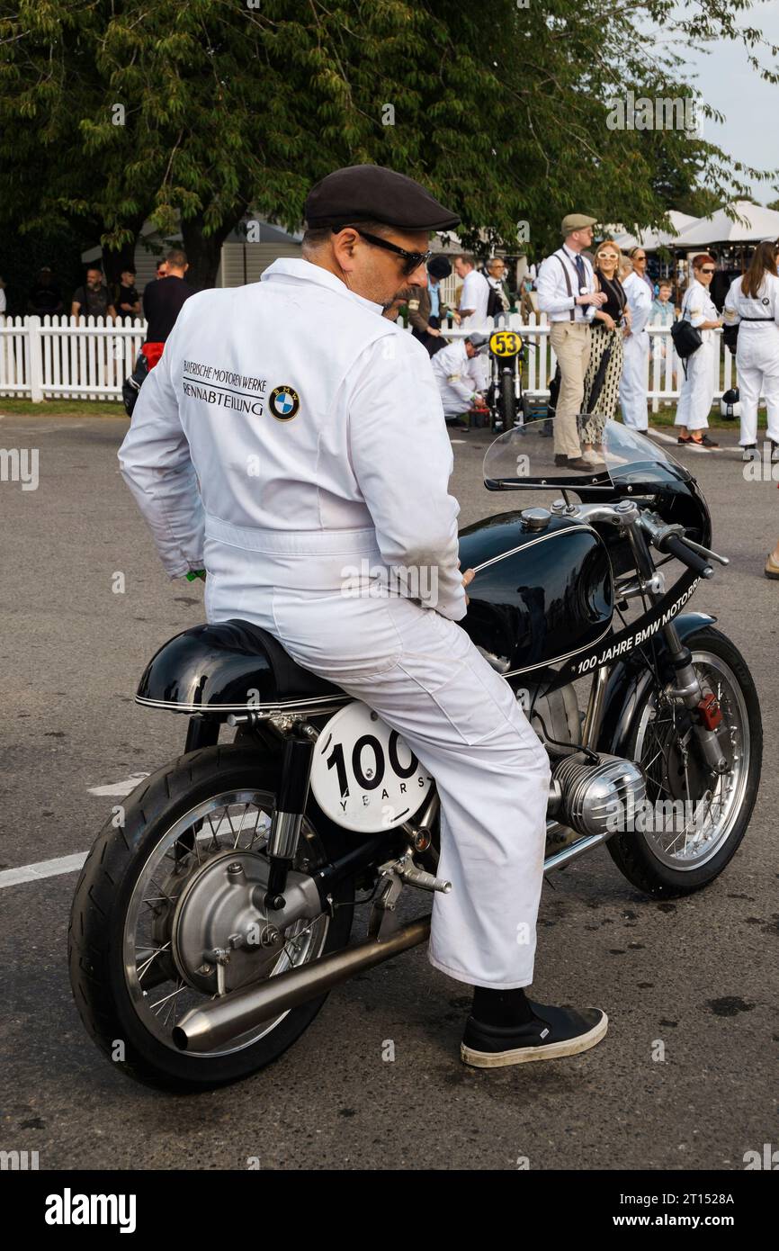 Mechanic sitting on a 1963 BMW Kaczor R50S in the Assembly Area at the BARC Revival Meeting 2023, Goodwood motor racing circuit, West Sussex, UK Stock Photo
