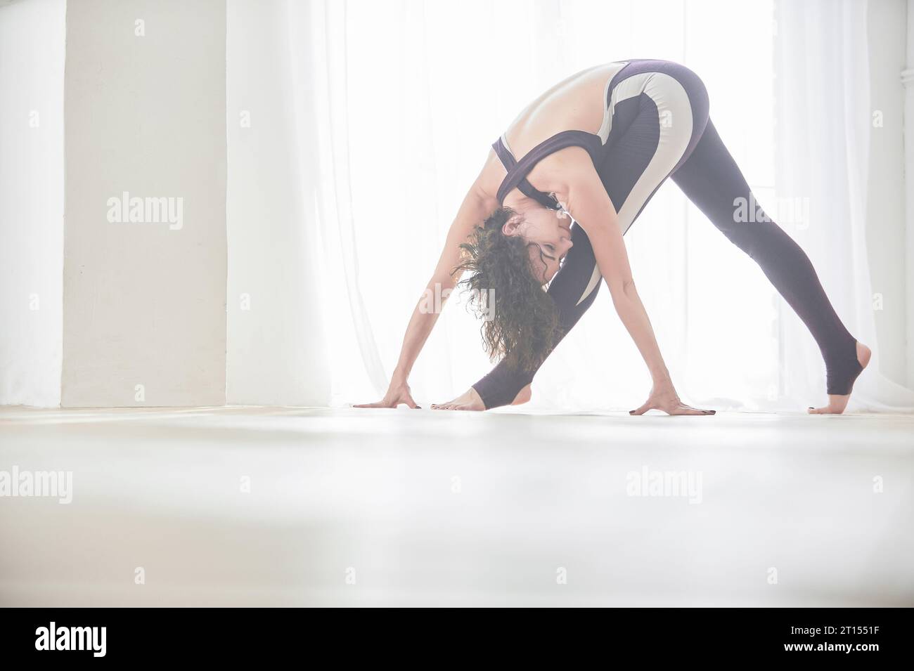 Beautiful young woman practices yoga asana Baddha Konasana - bound angle pose in the light yoga studio. Stock Photo