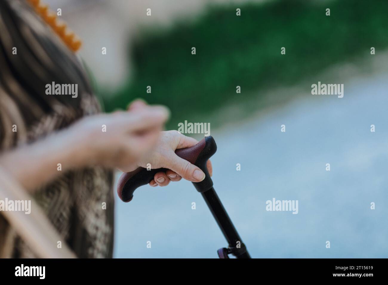 With her hand on a cane, full of age marks, an old lady cherishes her