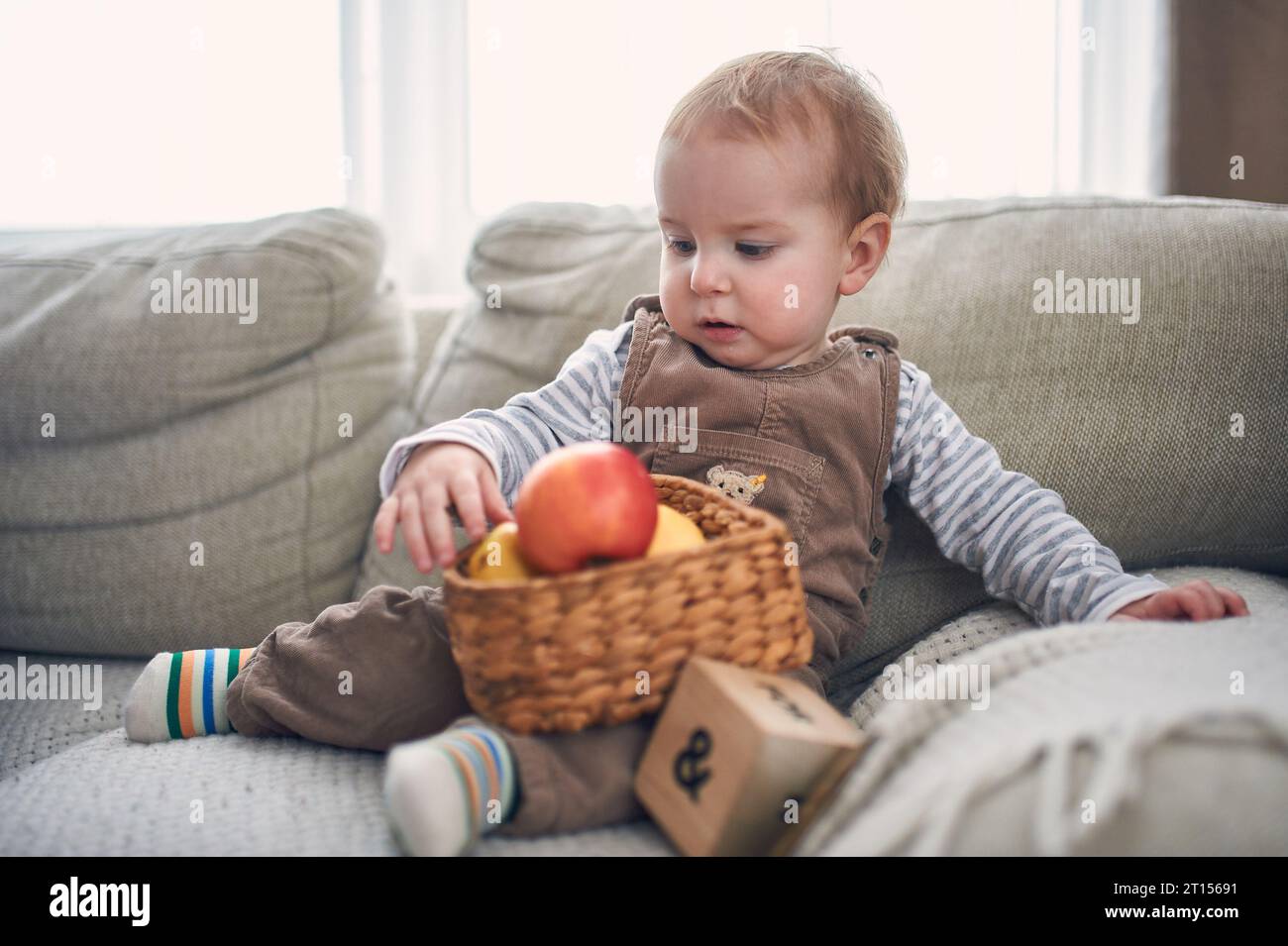 Portrait of a cute 1 year old baby boy sitting on a sofa. Stock Photo