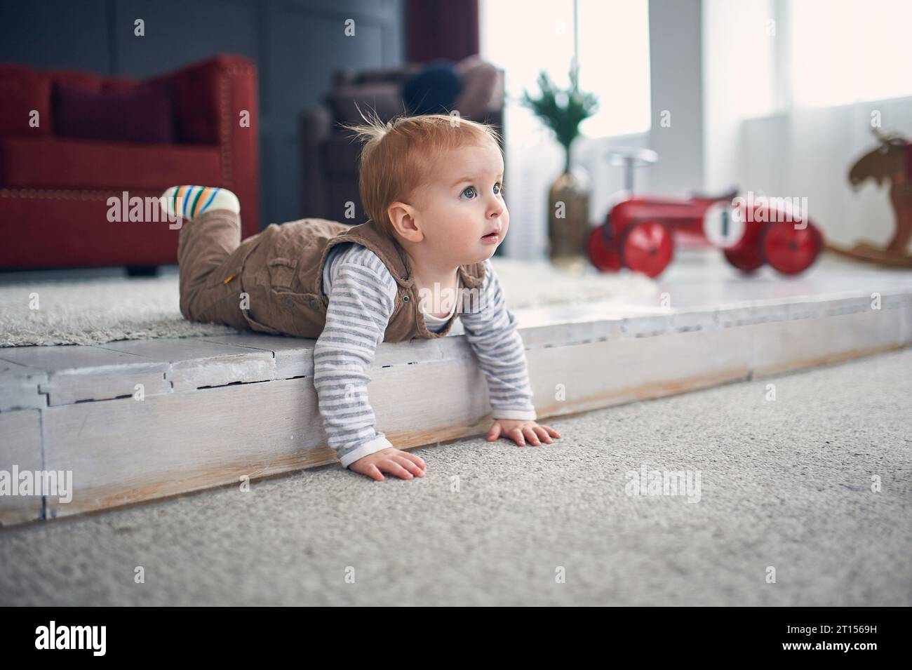 1 year old baby boy crawling on floor at home. christmas decorations on a background. Stock Photo