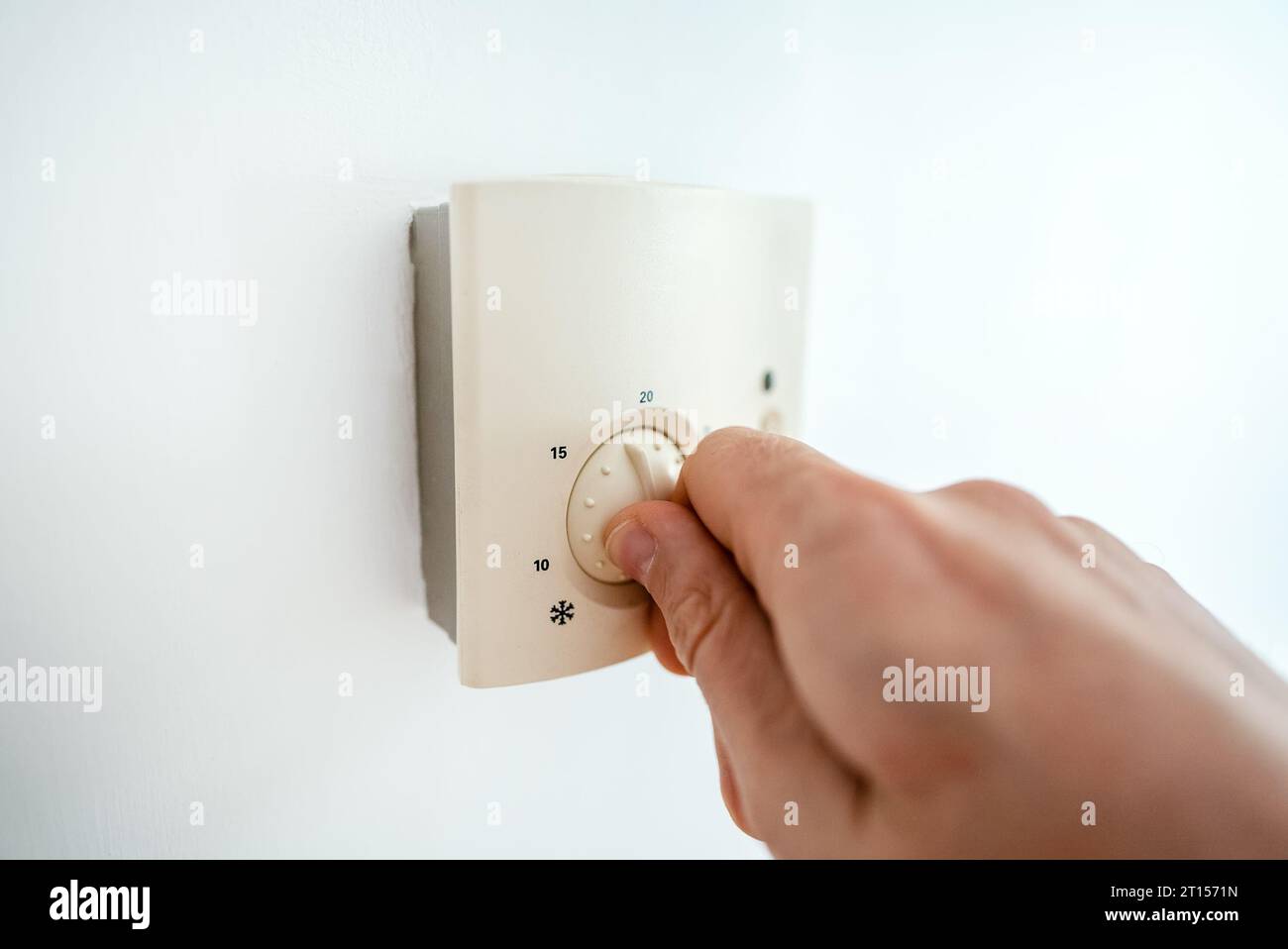 Man turning down heating thermostat to save money Stock Photo Alamy