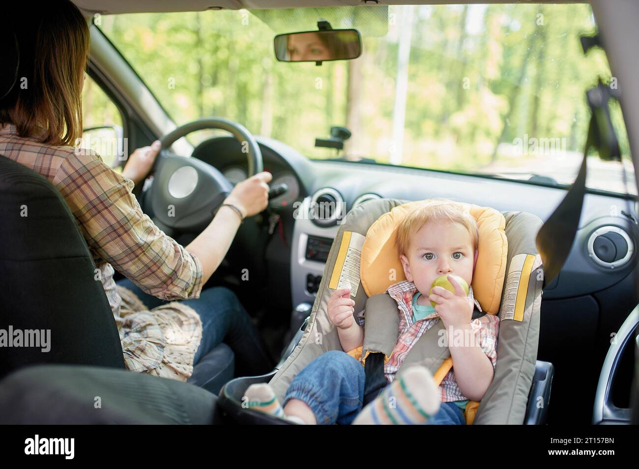 Young beautiful woman driving a car. On a front seat mounted child
