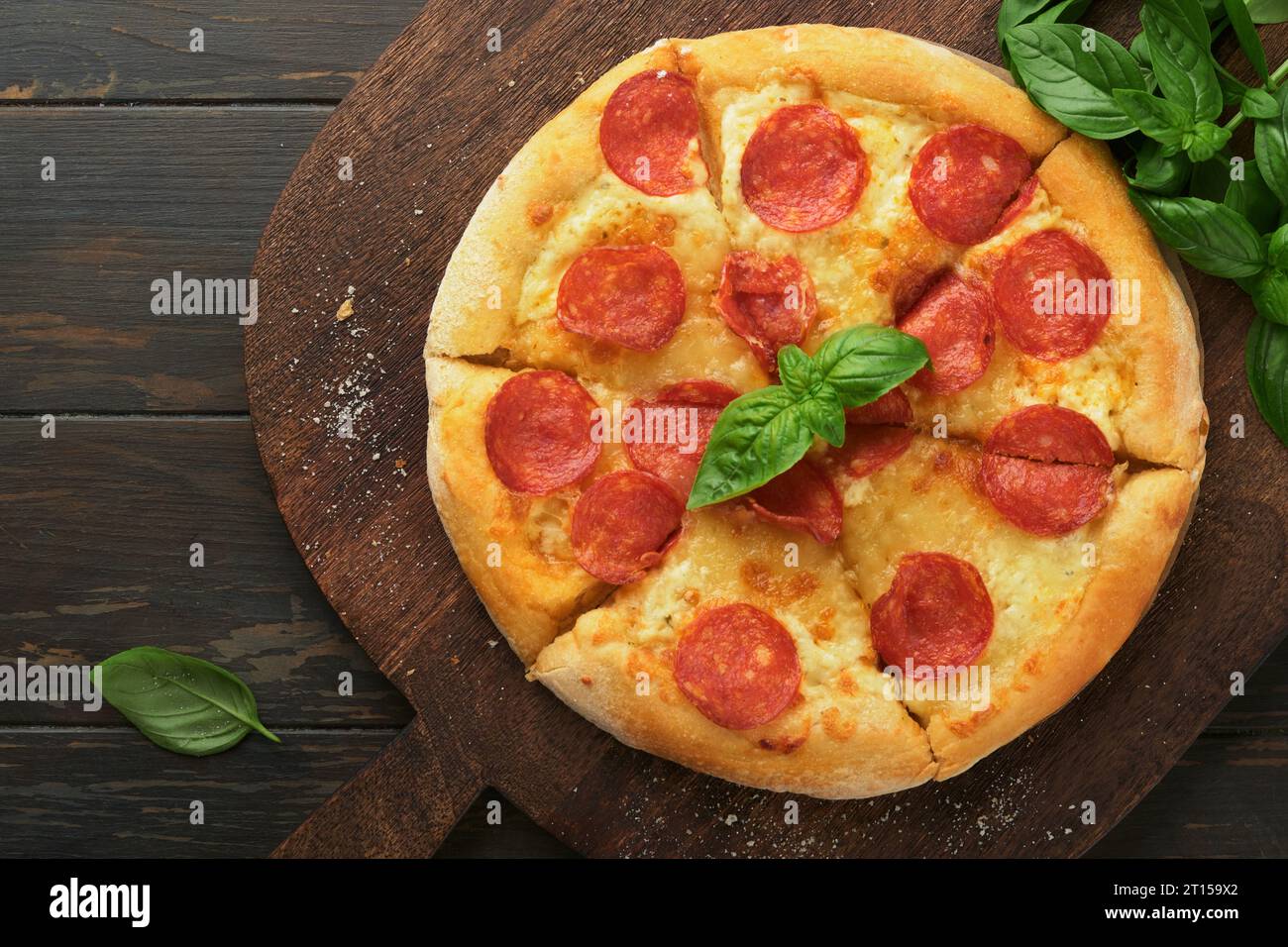 Pepperoni pizza. Traditional pepperoni pizza and cooking ingredients tomatoes basil on wooden table backgrounds. Italian Traditional food. Top view. M Stock Photo