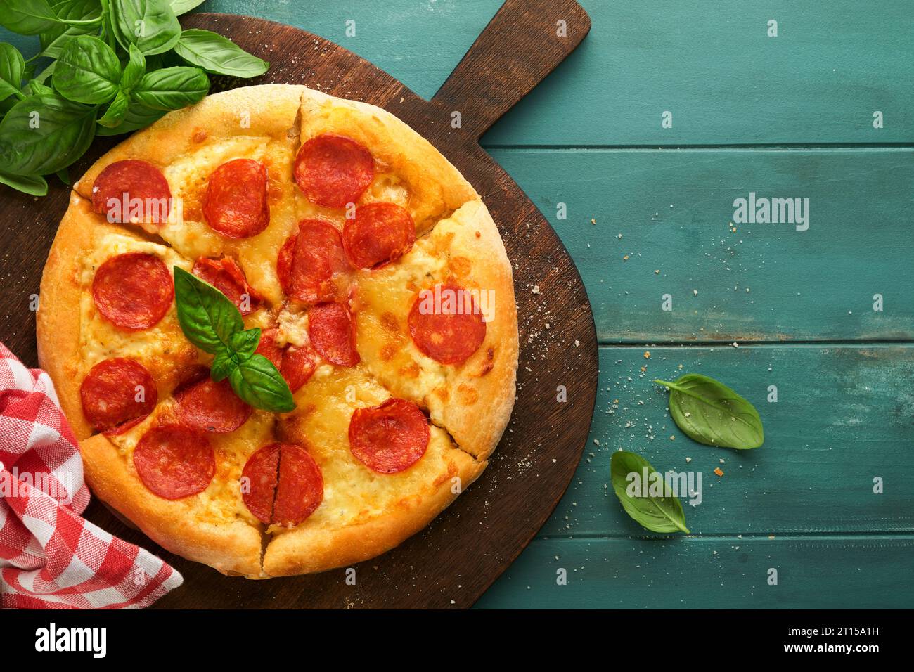 Pepperoni pizza. Traditional pepperoni pizza and cooking ingredients tomatoes basil on wooden table backgrounds. Italian Traditional food. Top view. M Stock Photo