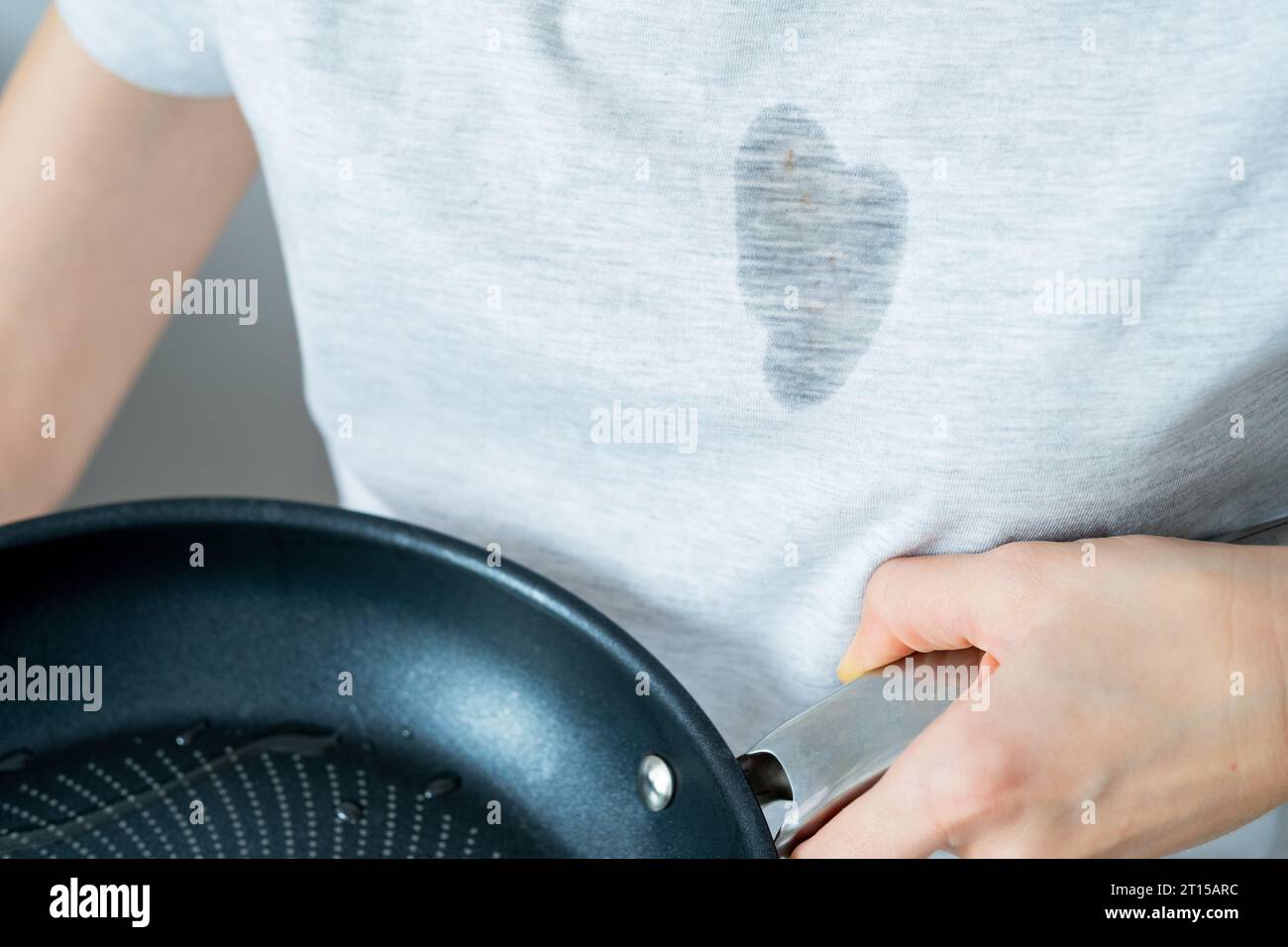 Tough grease stains in clothes. An unrecognized woman is holding a pan