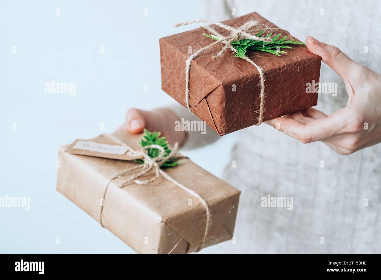 Female hands holding gift handcrafted boxes thoughtfully wrapped in eco-friendly packaging. Sustainable and eco-conscious living concept Stock Photo