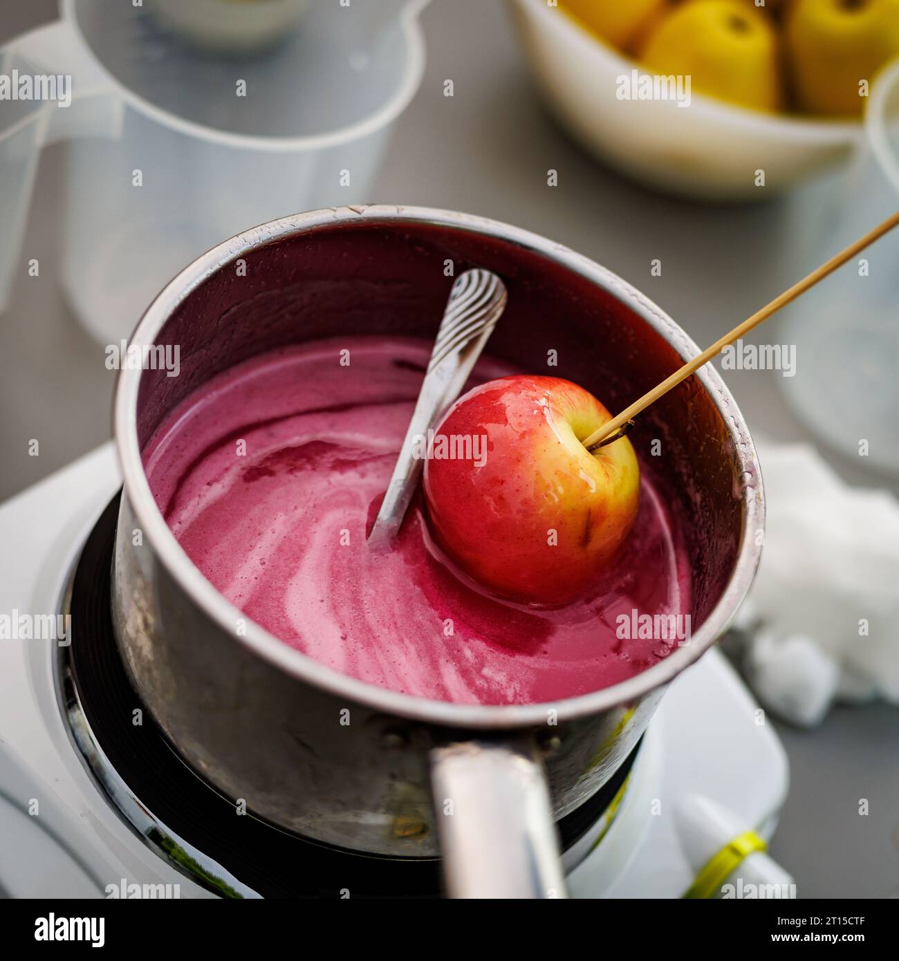 Dipping candy apple into glass bowl with caramel Stock Photo Alamy