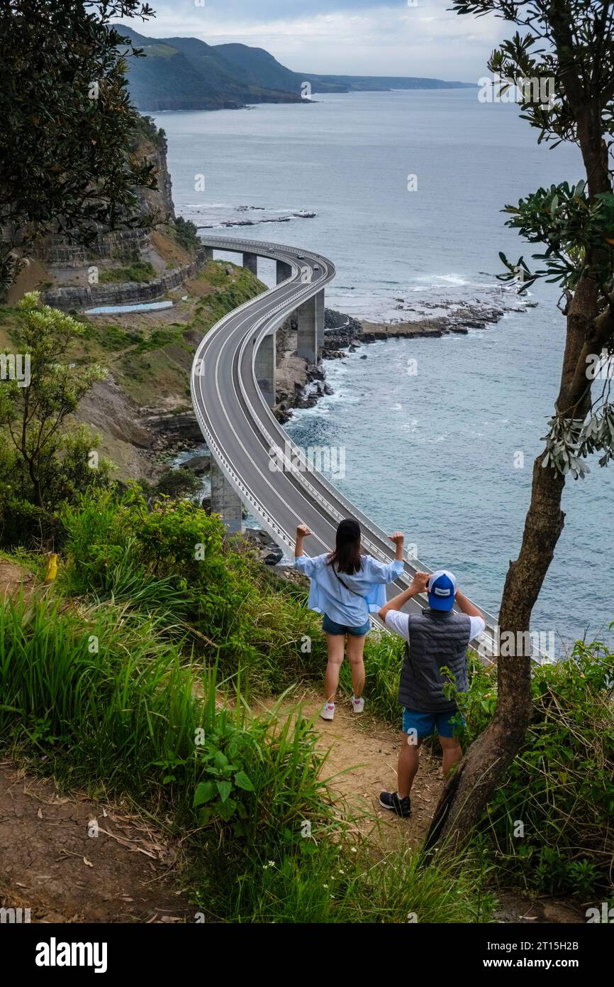 Tourist taking photographs with a backdrop of the Seacliff Bridge, Grand Pacific Drive, Clifton, New South Wales, Australia Stock Photo