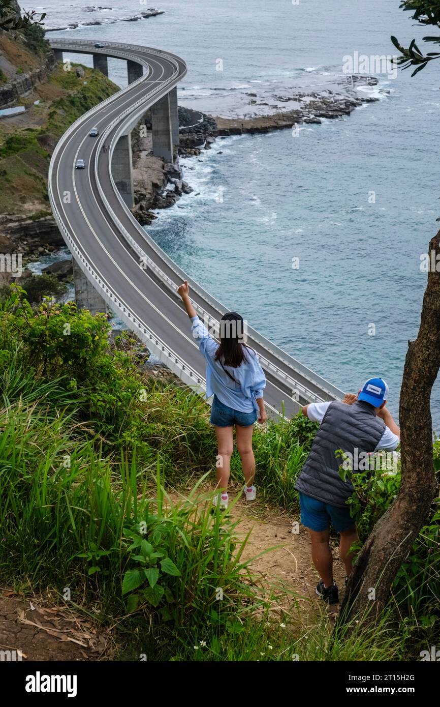 Tourist taking photographs with a backdrop of the Seacliff Bridge, Grand Pacific Drive, Clifton, New South Wales, Australia Stock Photo