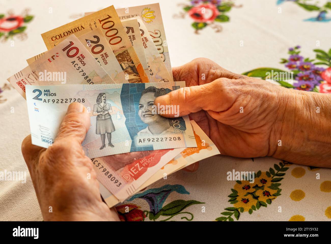 Colombian peso, a pensioner holds several banknotes in her hand, Financial problems of seniors, inflation and poverty in Colombia Stock Photo