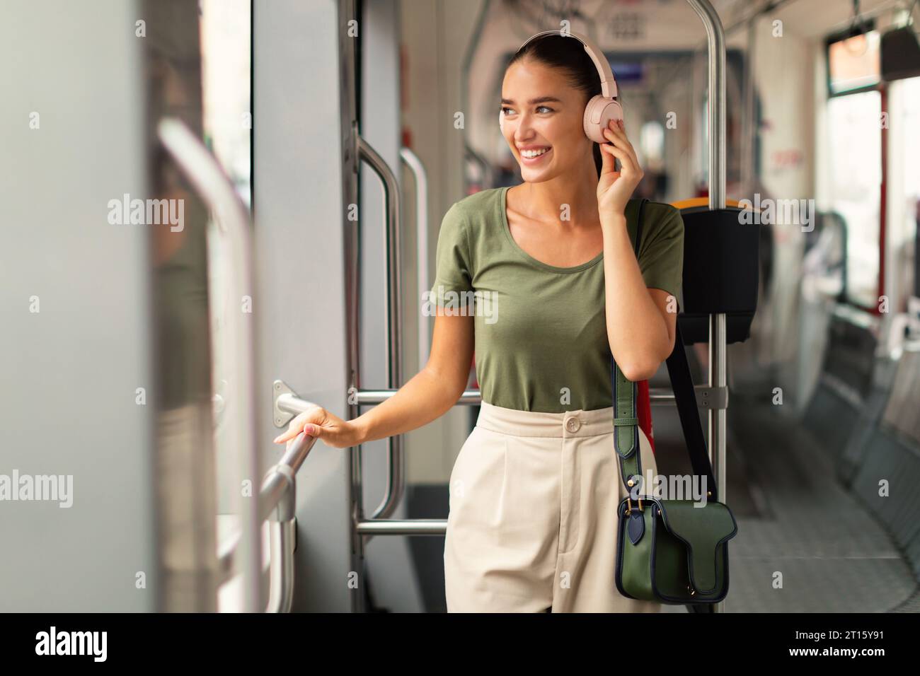 Woman immerses in music utilizing headphones traveling in city tram Stock Photo