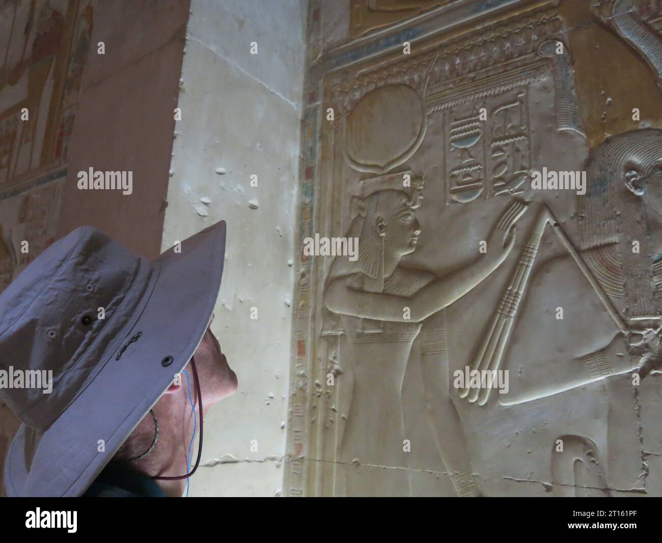 English male tourist in wide hat gazes up at the carvings on the wall at the Great Temple of Seti I at Abydos, historical necropolis of Ancient Egypt. Stock Photo