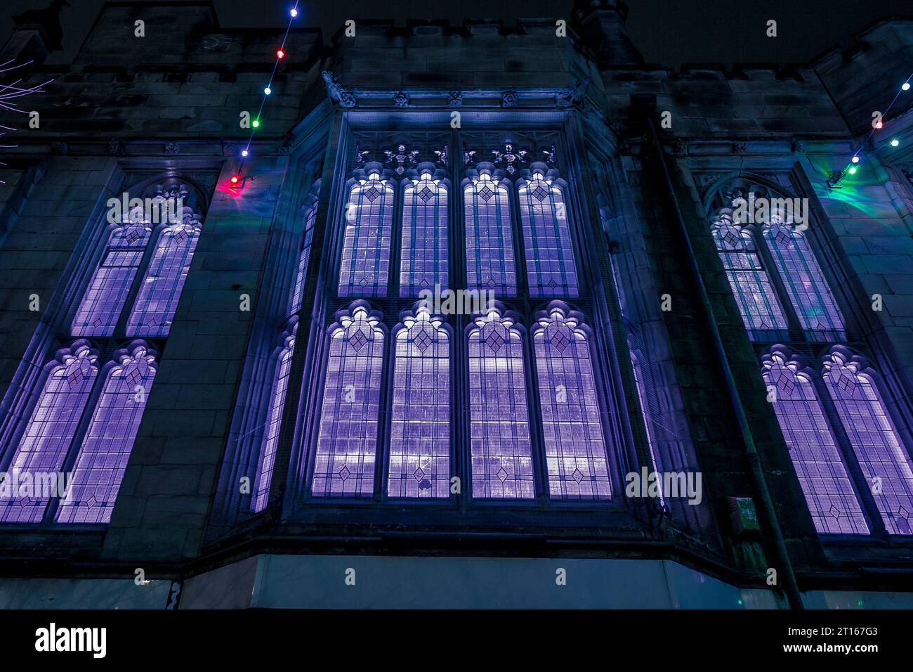 A vintage clock stands tall in front of illuminated stained glass ...