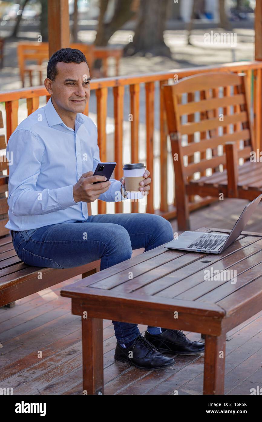 Latin man using a laptop while drinking coffee in a bar. Stock Photo