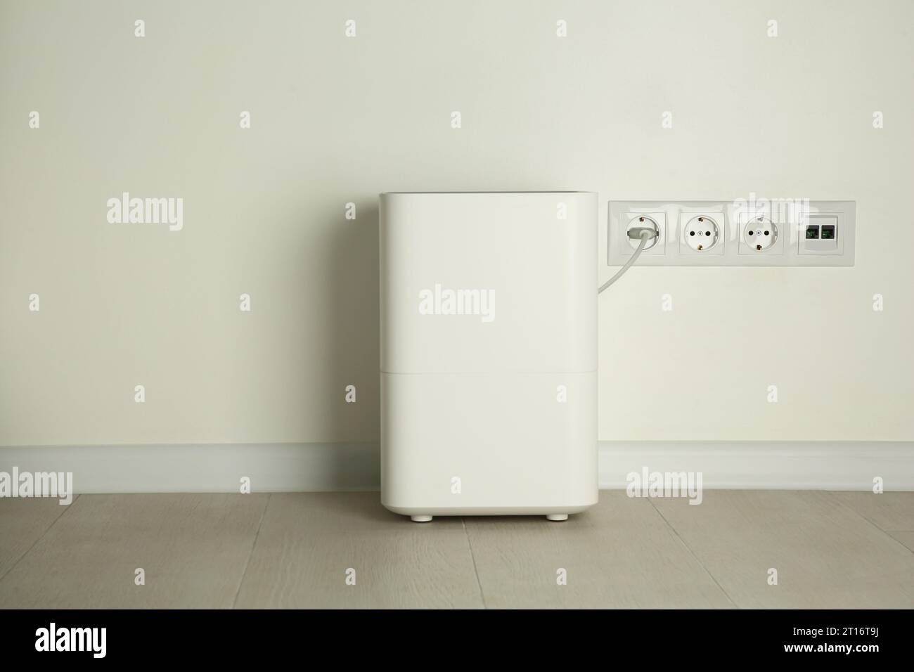 Modern air humidifier plugged into power socket on floor indoors Stock ...