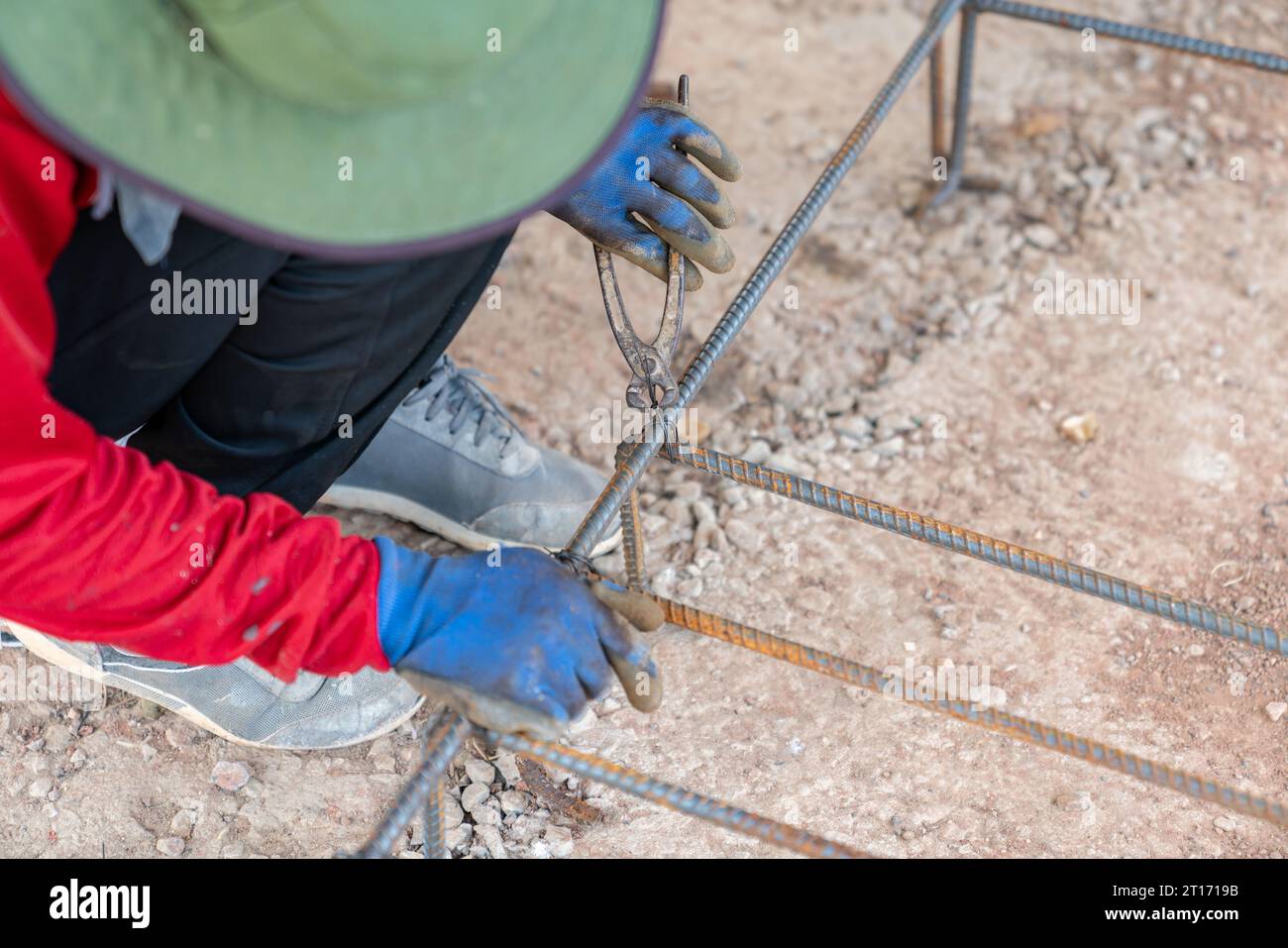Workers use pliers tie wire to rebar foundation to use as a base for