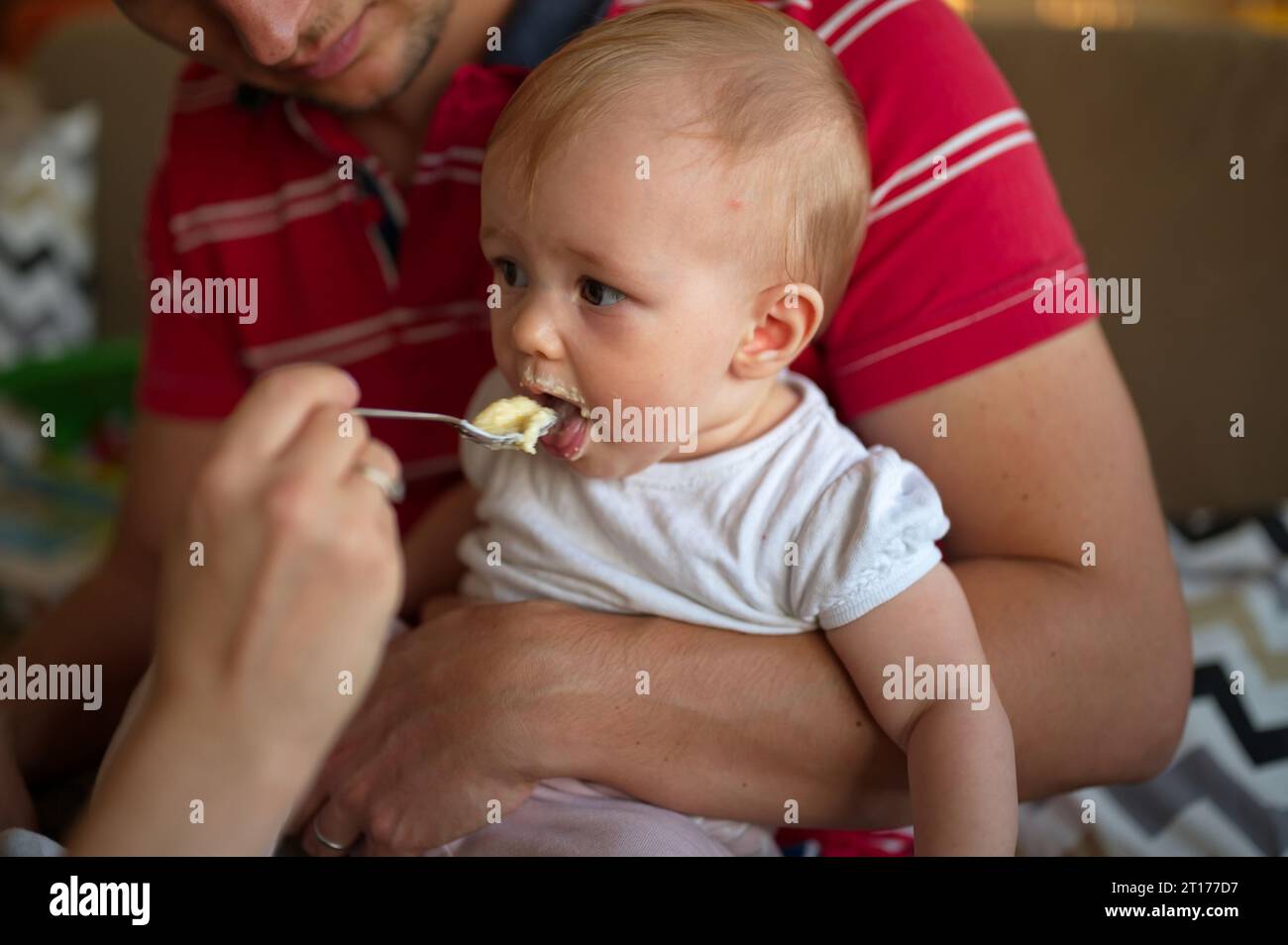 Midsection of parents feeding their baby girl with spoon Stock Photo
