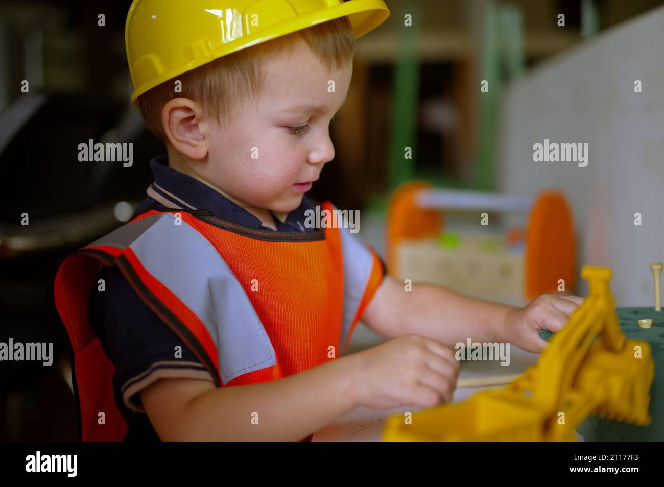 Little toddler dressed as a builder playing at home Stock Photo