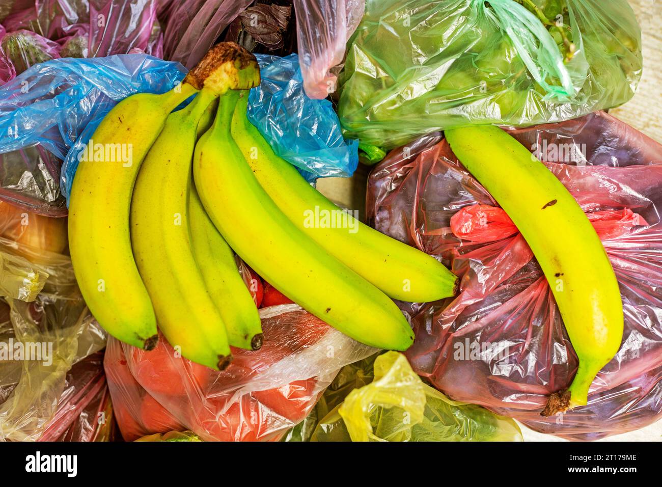 green bananas lie on top of other vegetables and fruits in multi