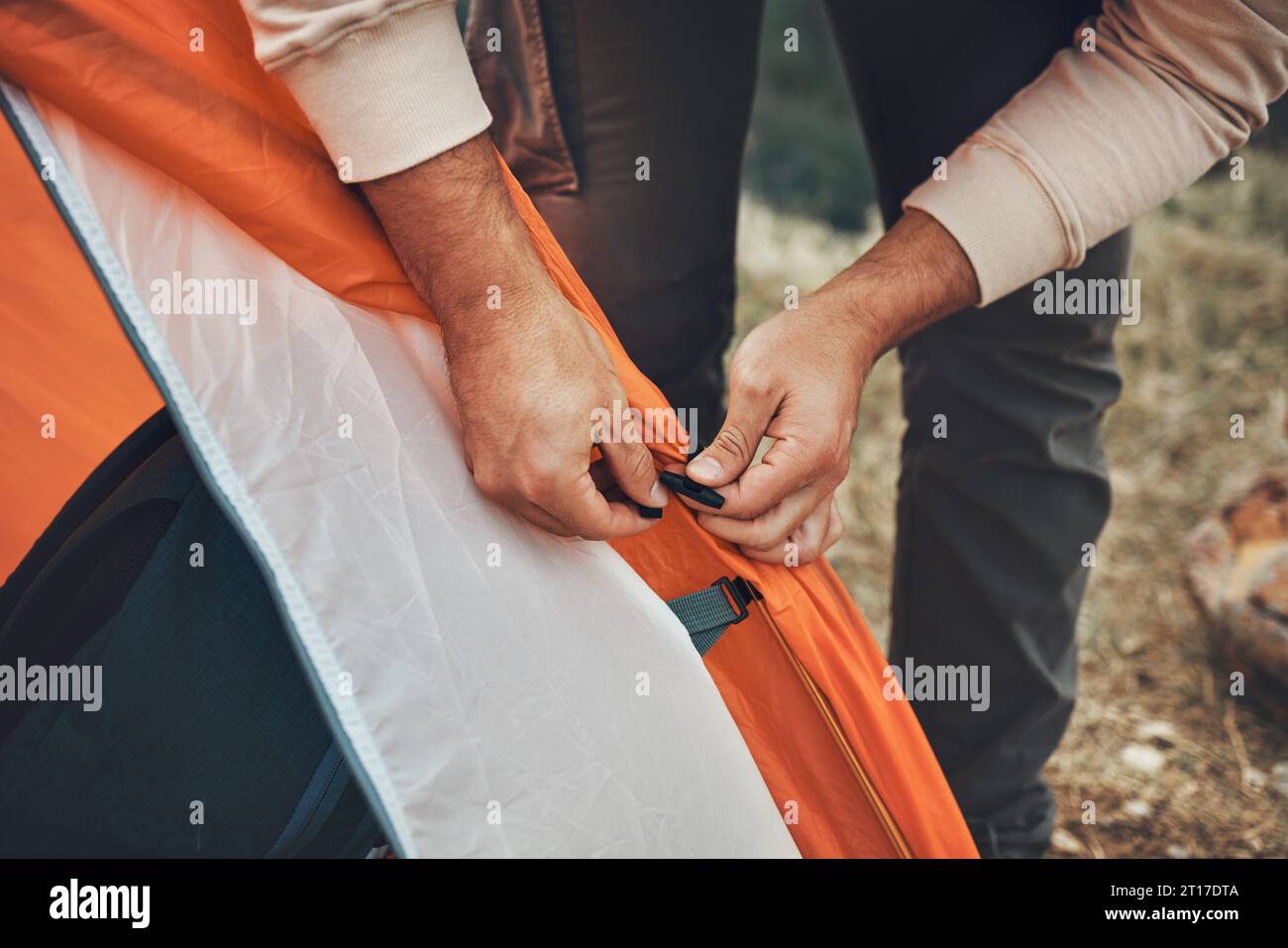 Hands, pitch tent and camping in nature on vacation, holiday or travel outdoor. Campsite, closeup and man set up shelter, tying and preparation for Stock Photo