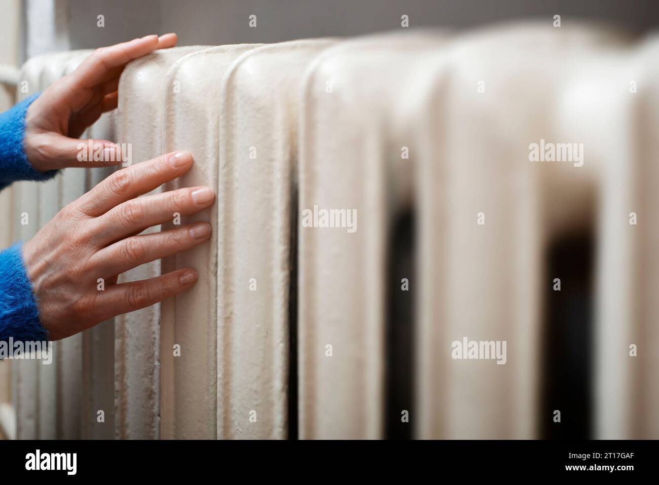 Caucasian female warming up hands near Hot Water Radiator. Space for text Stock Photo