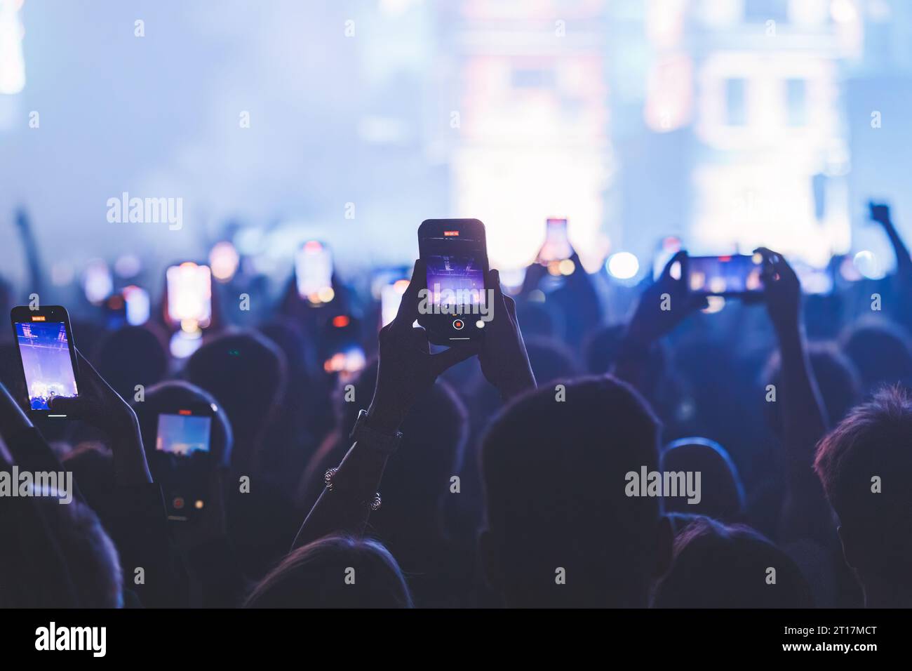 People taking pictures and recording at the big concert. Closeup shot