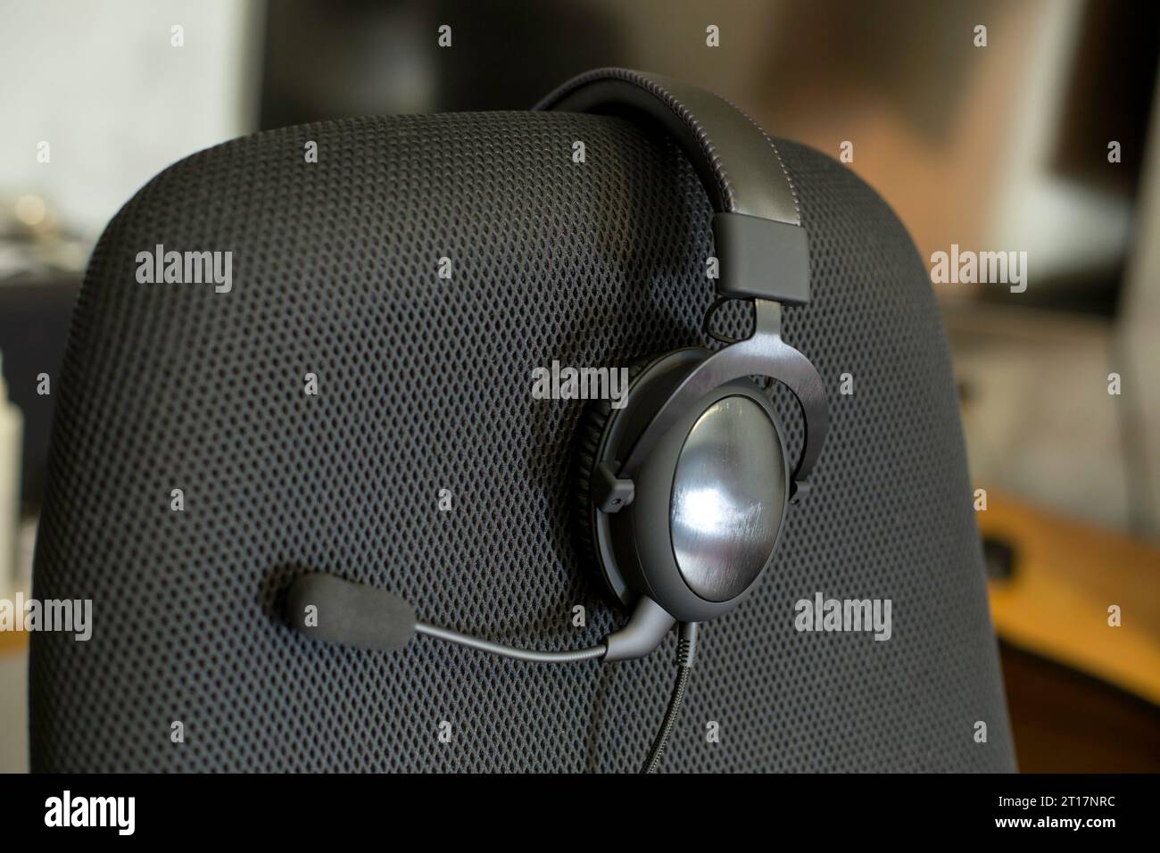 black headset on backrest of empty computer chair with air mesh upholstery Stock Photo