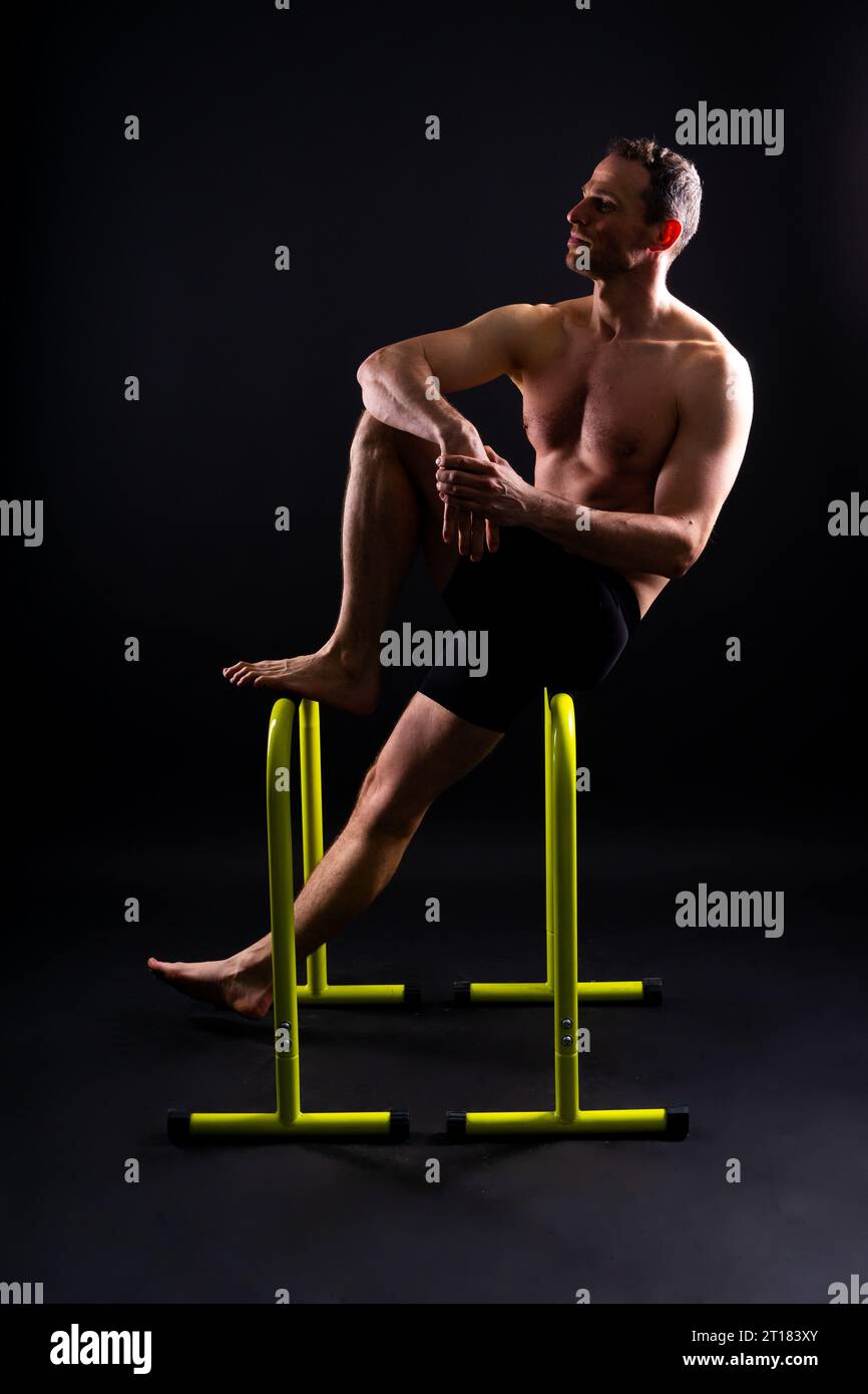 Front and side view photo of an strong young man exercising on parallel ...