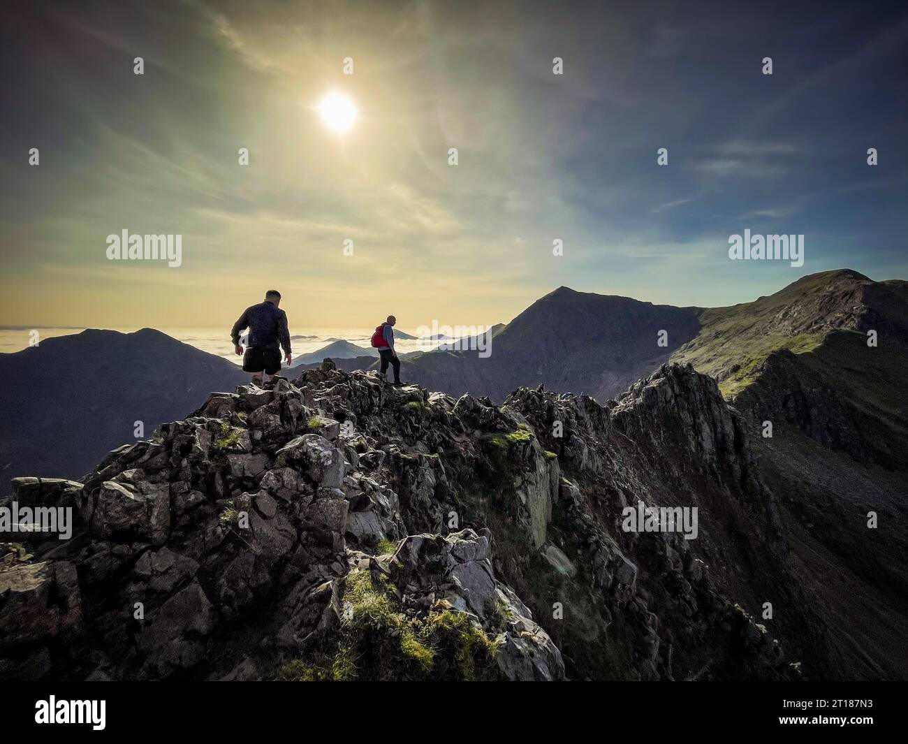 Male climbers on the challenging Crib Goch with Cri-y-ddysgl and Snowdon in the distance and Y Lliwedd to left on a sunny Autumn day. Wales. UK. Stock Photo