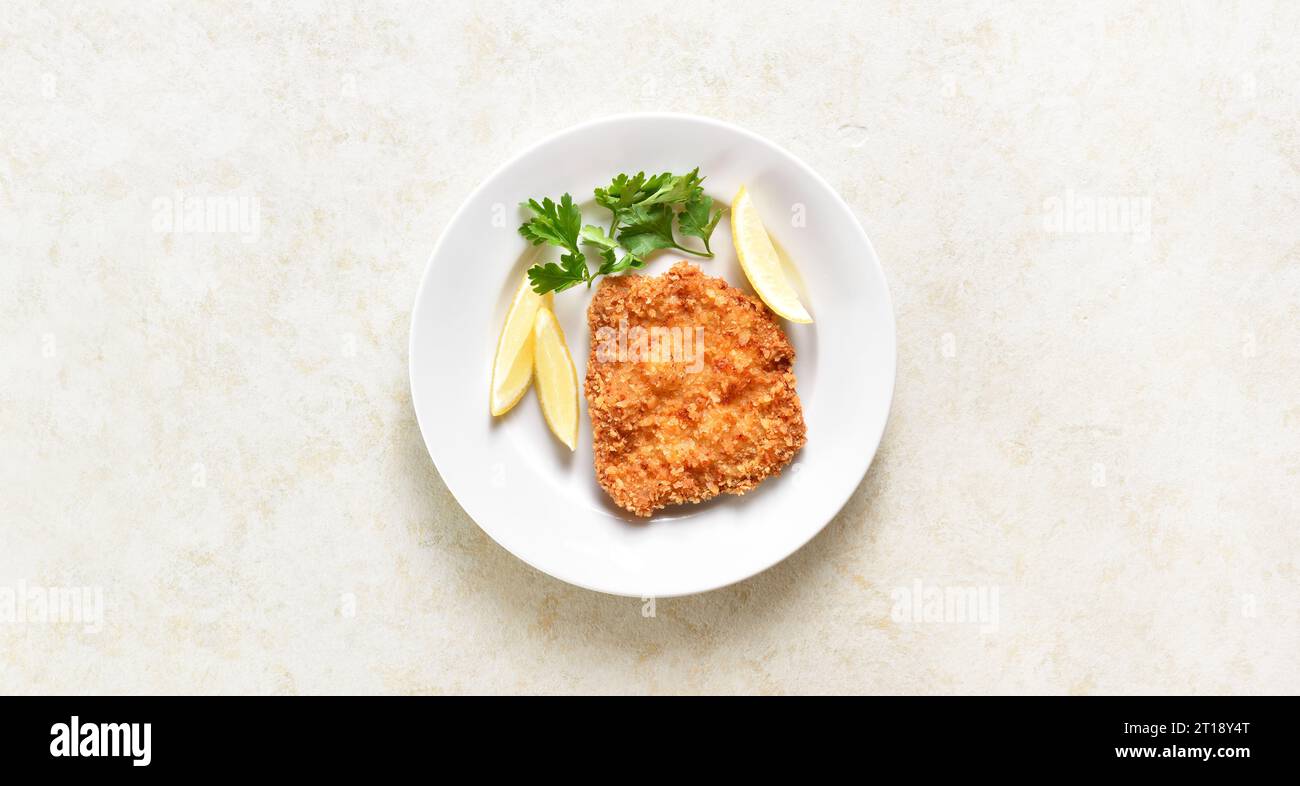 Homemade breaded chicken schnitzel on plate over light stone background with copy space. Top view, flat lay Stock Photo