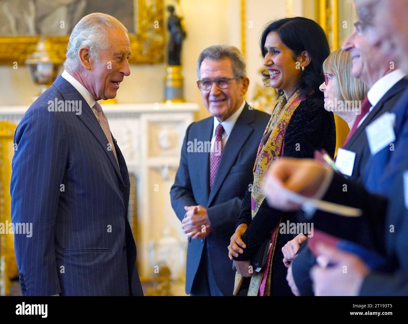 King Charles III talks to guests as he presents the 2022 and 2023 Queen