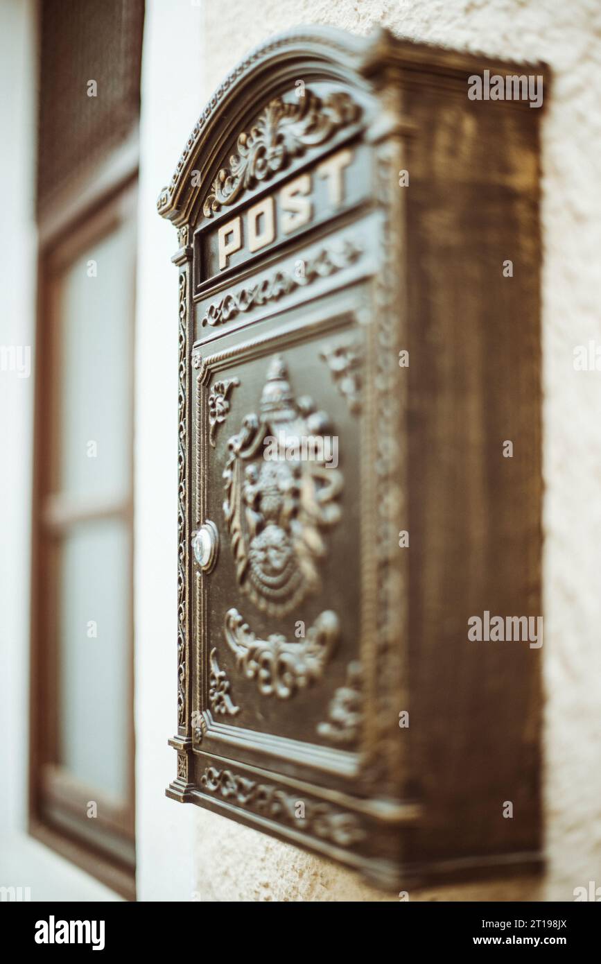 Close-up of metal mailbox hanging on a wall next to a window Stock Photo