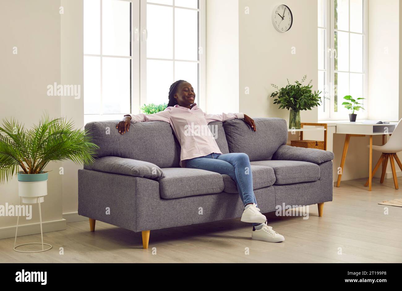 Happy young African American woman relaxing on a comfortable sofa in ...