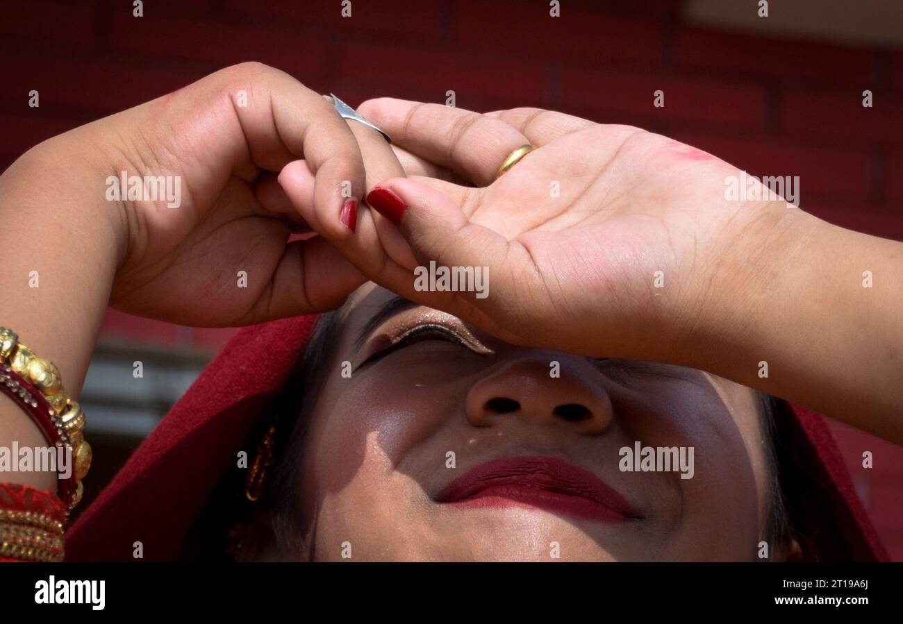 Lalitpur, Bagmati, Nepal. 12th Oct, 2023. A girl from Newar community looks at the sun during a ritual of ''Barah'', a traditional marriage to the sun in Lalitpur, Nepal on October 12, 2023. Girls from Newar community pass through a tradition of marrying Sun God before puberty by staying inside a room without sunlight for 12 days and then coming out for a meeting in a function symbolizing a celestial marriage ceremony. Girls from Newar community are married thrice in their life, to the bael fruit and the sun before marrying a human. (Credit Image: © Sunil Sharma/ZUMA Press Wire) EDITORIAL US Stock Photo