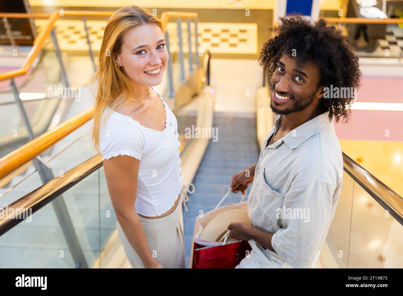 A couple while shopping, they are on the escalators with their purchases Stock Photo