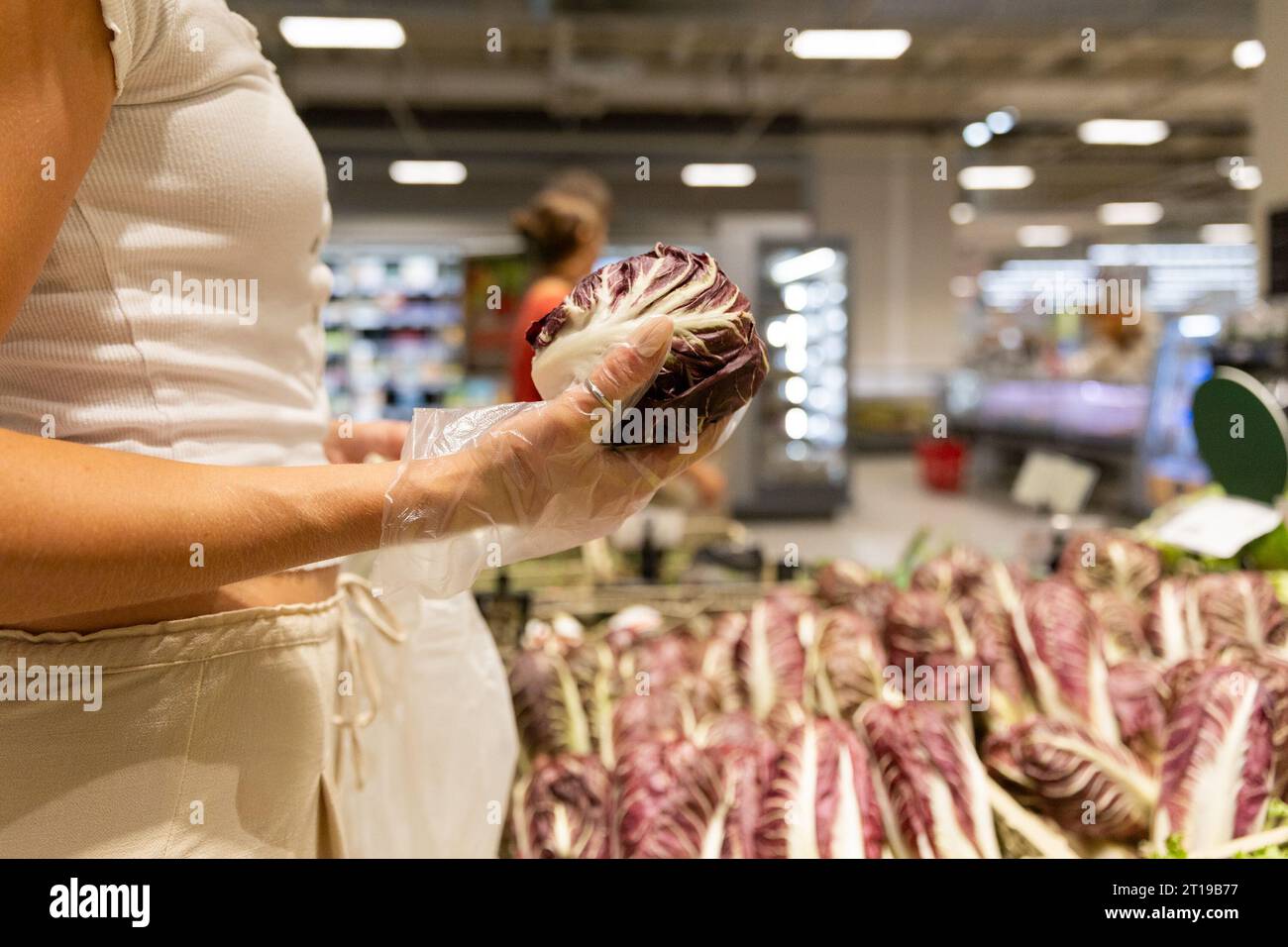 Close-up of a woman's hand choosing a purple cabbage in the fruit and vegetable section of the supermarket Stock Photo