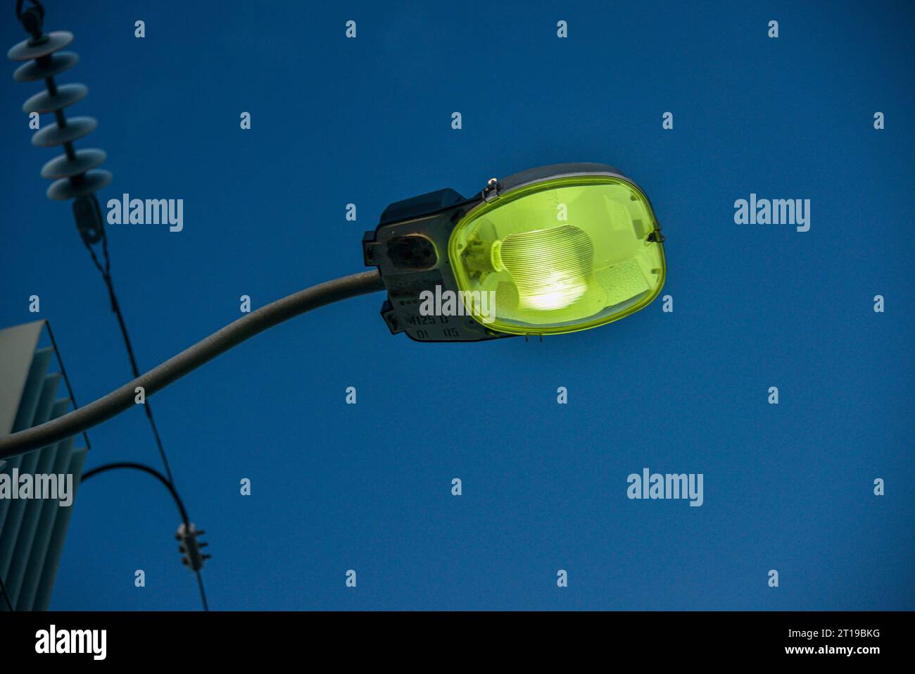 Close up view of a (green) Sodium Vapour street lamp, with blue sky in