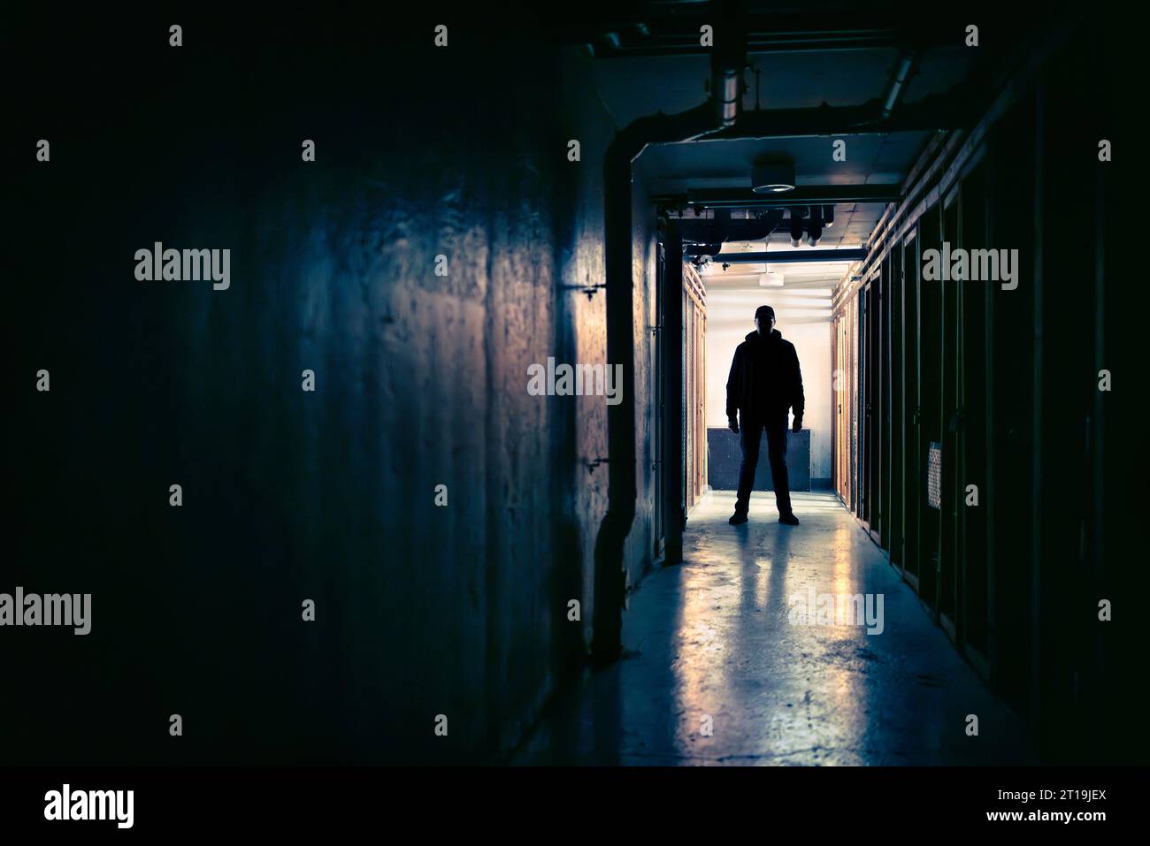 Killer, creepy, scary stalker man in dark corridor. Horror, thriller movie concept. Suspicious silhouette and figure in shadow. Maniac psycho criminal. Stock Photo