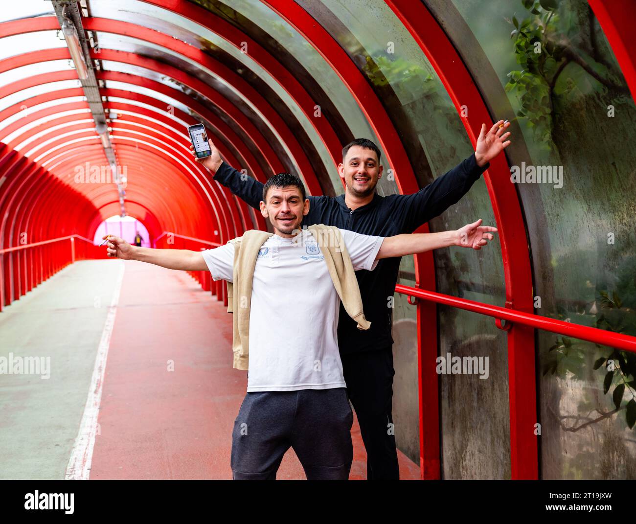 Two likely locals happily posing with phones and cigarettes in their hands and insistent that their photo was taken in the SECC tunnel/ bridge Stock Photo