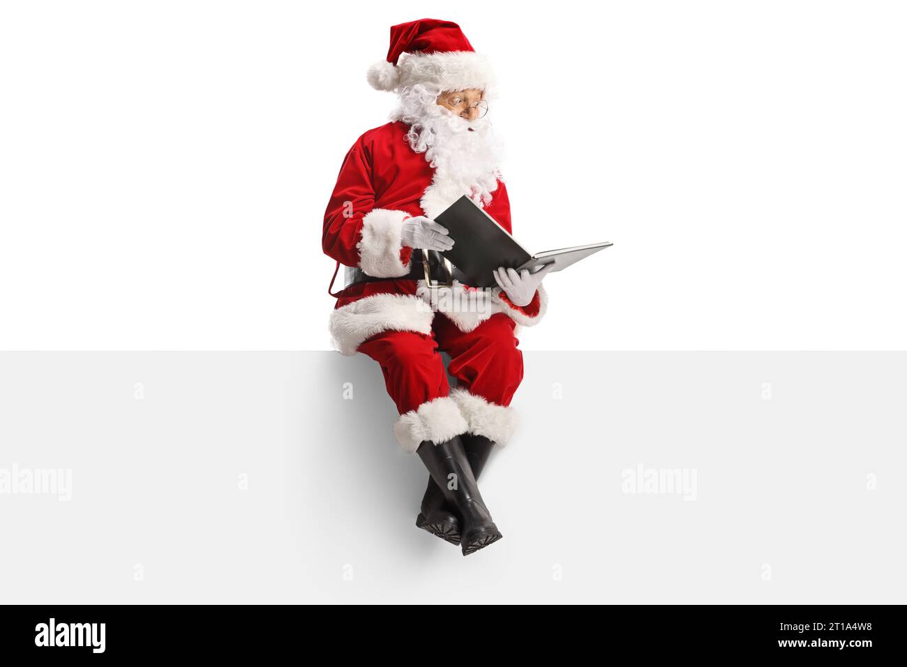 Santa claus sitting on a blank panel and reading a book isolated on ...