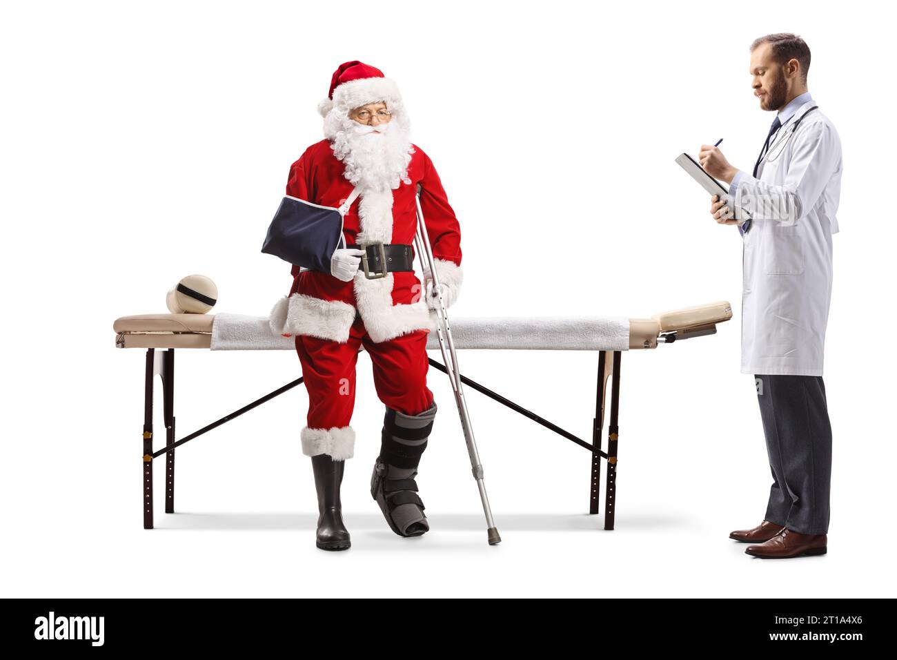 Santa claus with injured leg and arm sitting on a mat table and doctor writing a document isolated on white background Stock Photo
