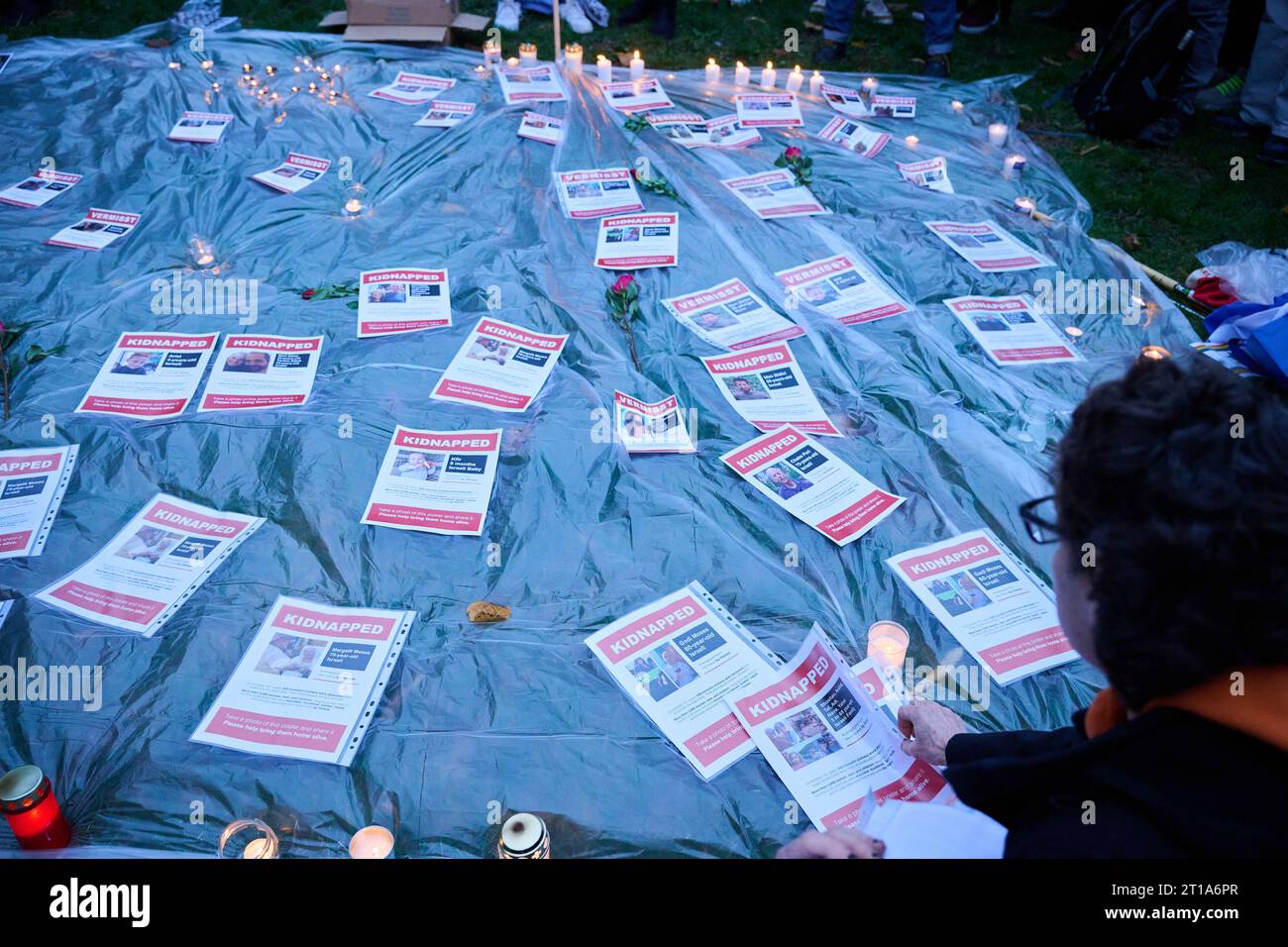 Berlin, Germany. 12th Oct, 2023. People lay on the ground sheets of paper with missing persons notices of people who have fallen victim to the Hamas attack in Israel. They gathered at Wittenbergplatz for a memorial event under the slogan 'Remembering the victims of Hamas terror. Solidarity with the people of Israel and Palestine.' At the event, the names of the missing were read out. Credit: Annette Riedl/dpa/Alamy Live News Stock Photo